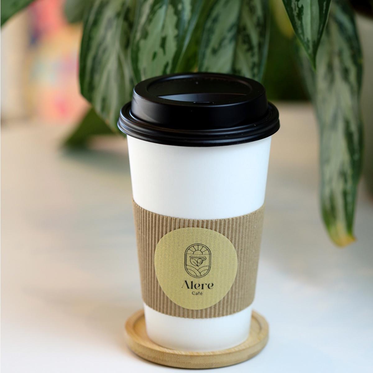 Vaso de Alere Café con el logo, entre plantas