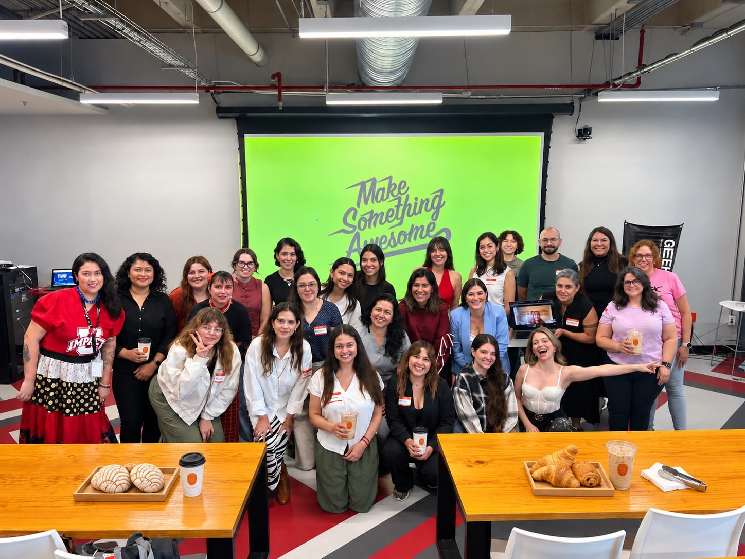 Grupo de asistentes posando al final de un taller, con bebidas y panadería de Alere servidas en las mesas